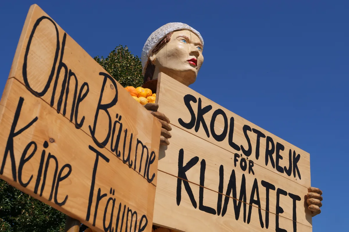Greta Thunberg als Kürbisfigur, mit Holzschild in der Hand
